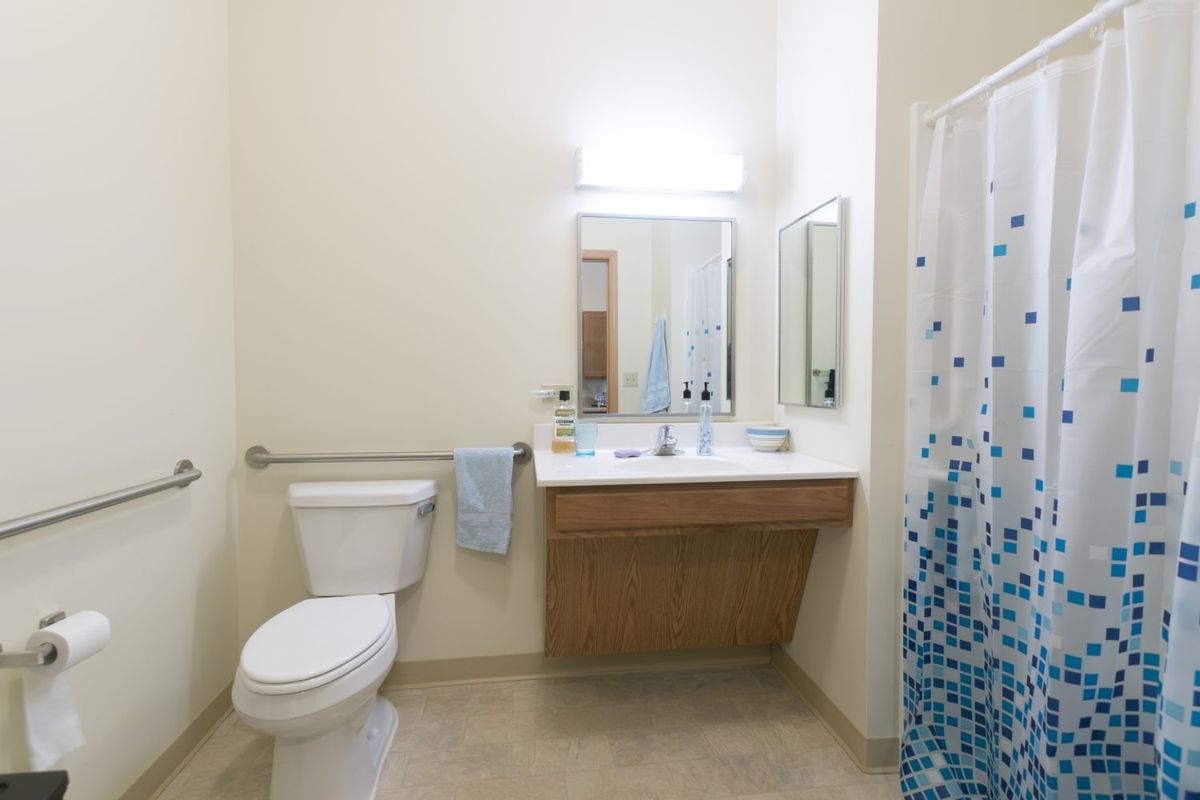 A clean and modern bathroom with a toilet, sink, mirror, and shower curtain.