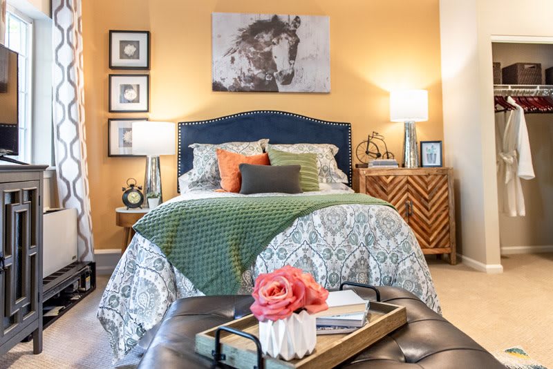 A cozy bedroom with a beautifully decorated bed, bedside lamps, and artwork on the wall, creating a warm and inviting atmosphere.