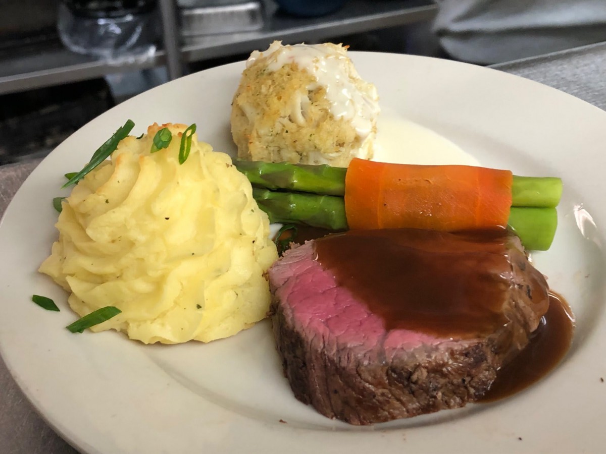 Gourmet steak dinner served with creamy mashed potatoes, asparagus, carrots, and a savory sauce.