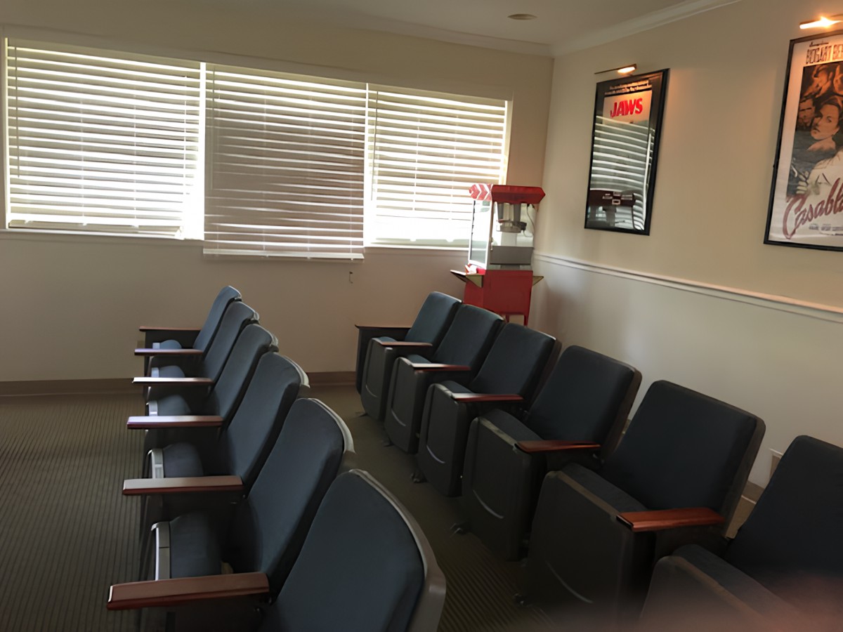 A cozy waiting room featuring a row of chairs, a popcorn machine, and decorative posters on the wall.