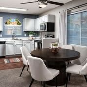 A modern kitchen and dining area featuring white cabinets, a round table with chairs, and large windows.