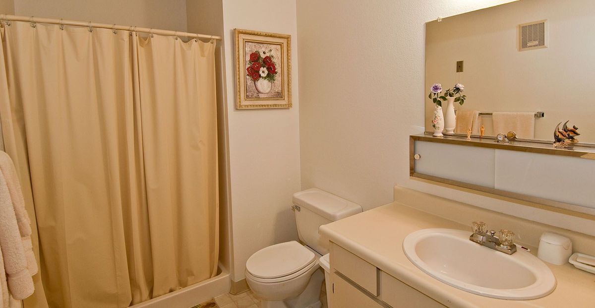 A compact bathroom with a shower, toilet, and sink, featuring simple decor.