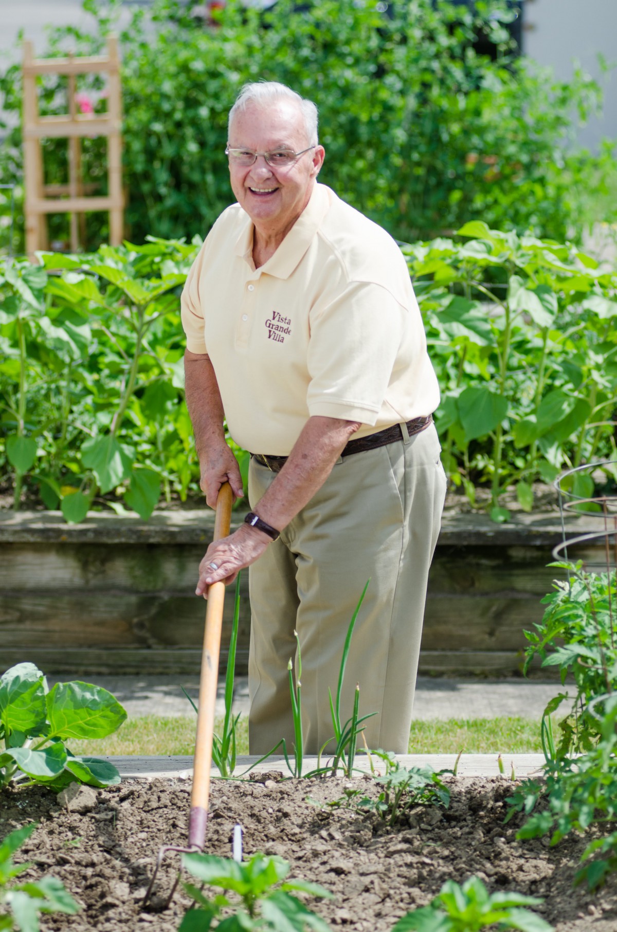 A man gardening outdoors with a garden tool.