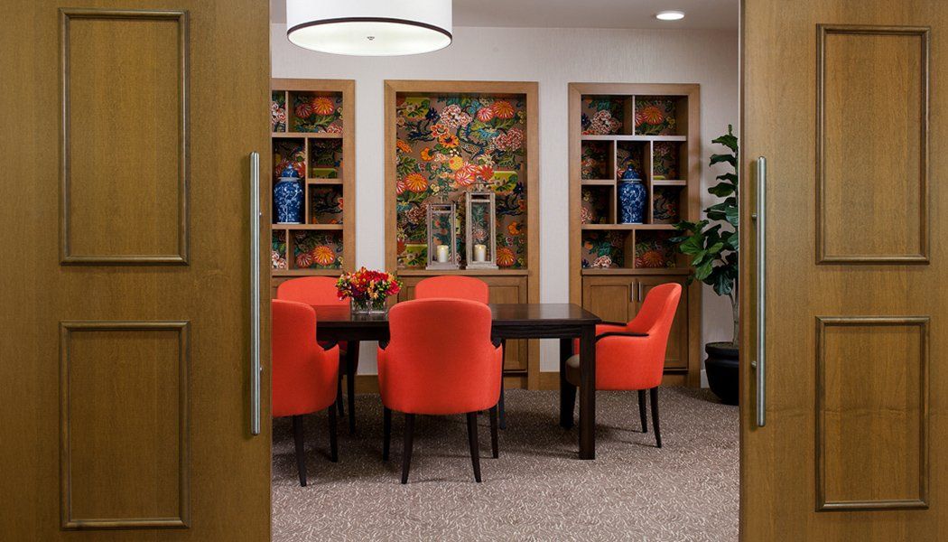 A cozy dining area with vibrant orange chairs and decorative bookshelves.