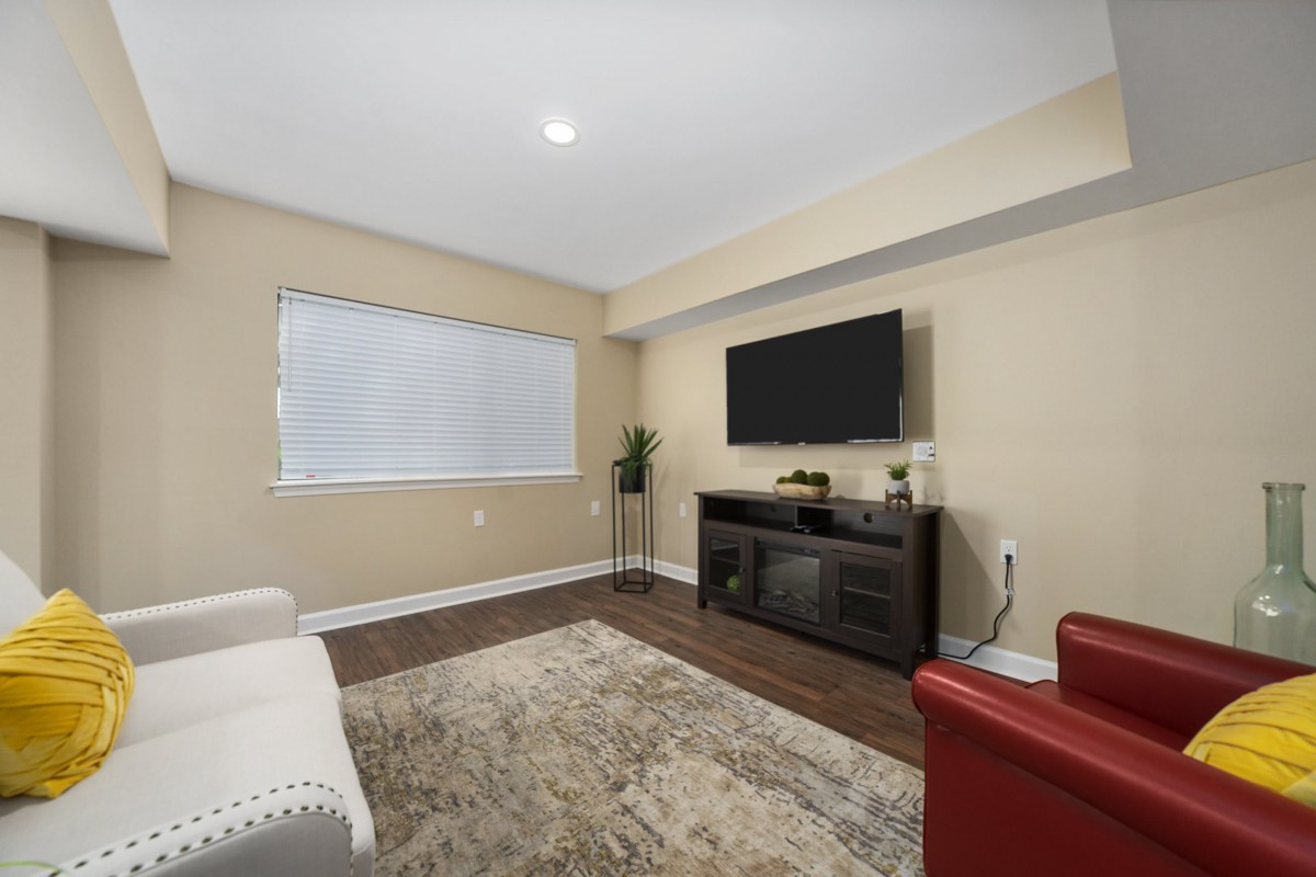 A modern living room with a flat-screen TV, couch, and wooden flooring.