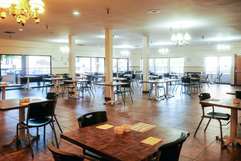 An empty dining hall with neatly arranged tables and chairs.