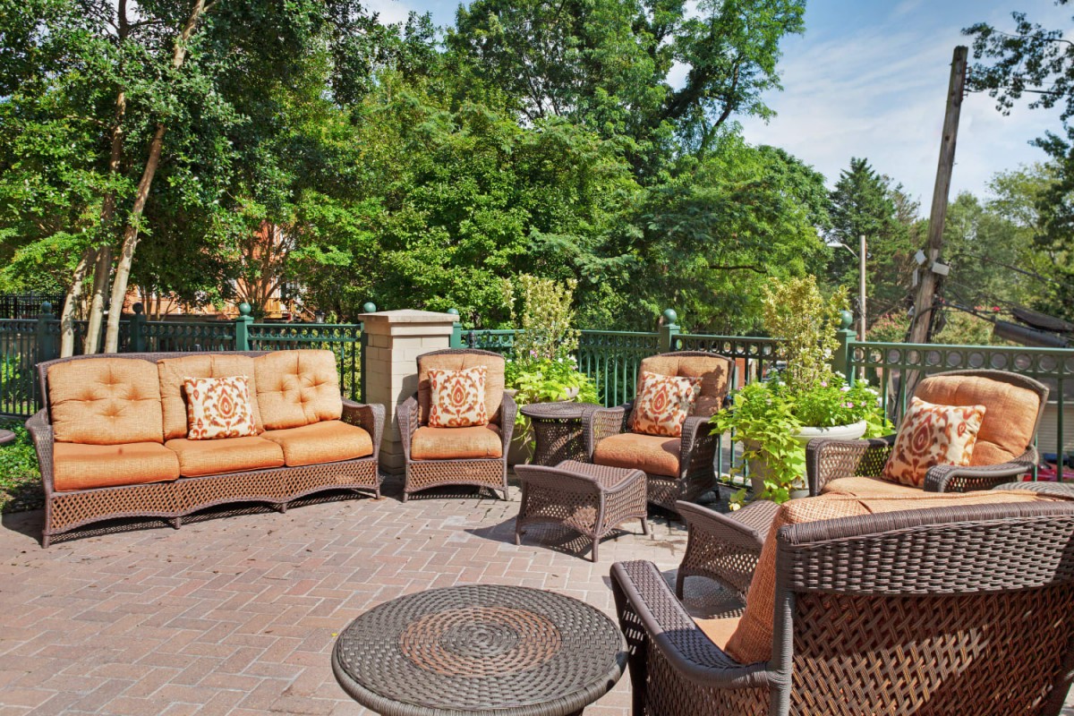 A cozy outdoor patio with comfortable seating surrounded by lush greenery.