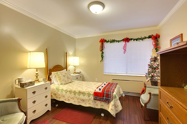 A cozy bedroom decorated with Christmas-themed items and a single bed.