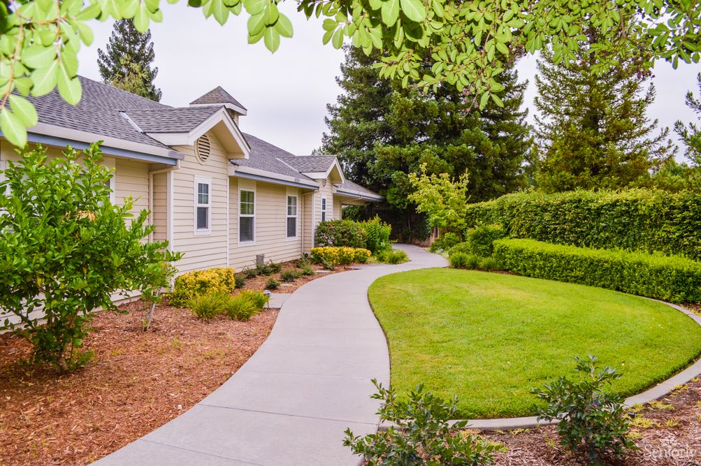 A peaceful residential property with a well-maintained lawn and garden, featuring a curved pathway leading to the house.