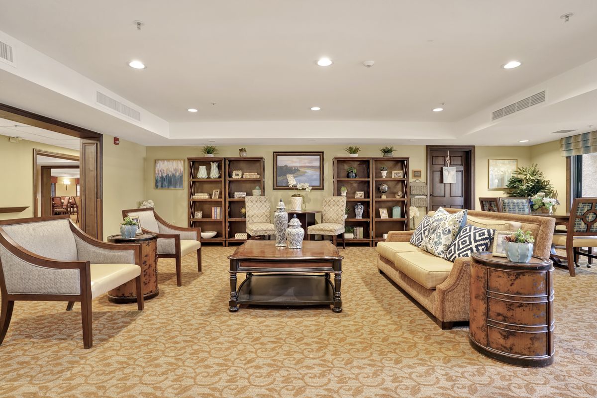 A spacious living room with elegant decor, featuring comfortable sofas, a central coffee table, and bookshelves lining the walls.