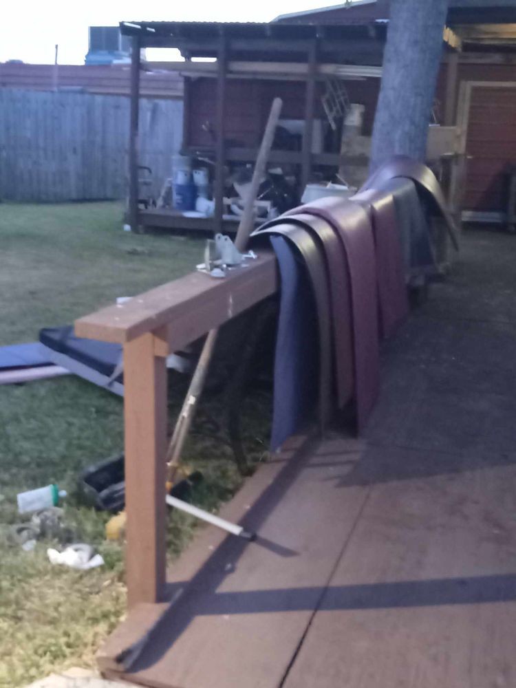 Several mats are draped over a fence in an outdoor yard area during the evening.