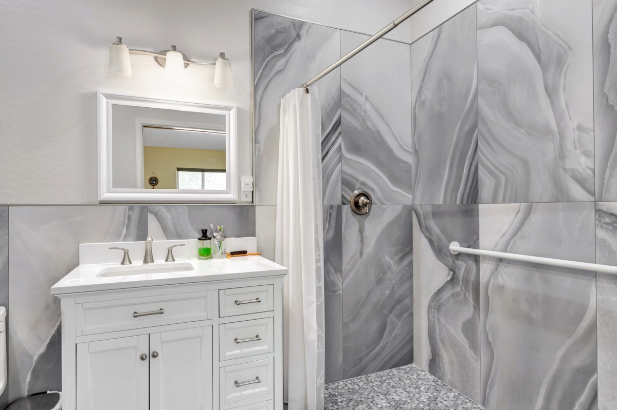 A modern bathroom featuring a marble-patterned shower and a white vanity.