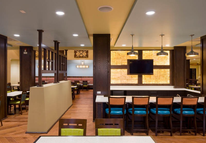Modern restaurant interior with colorful seating and a mounted television.