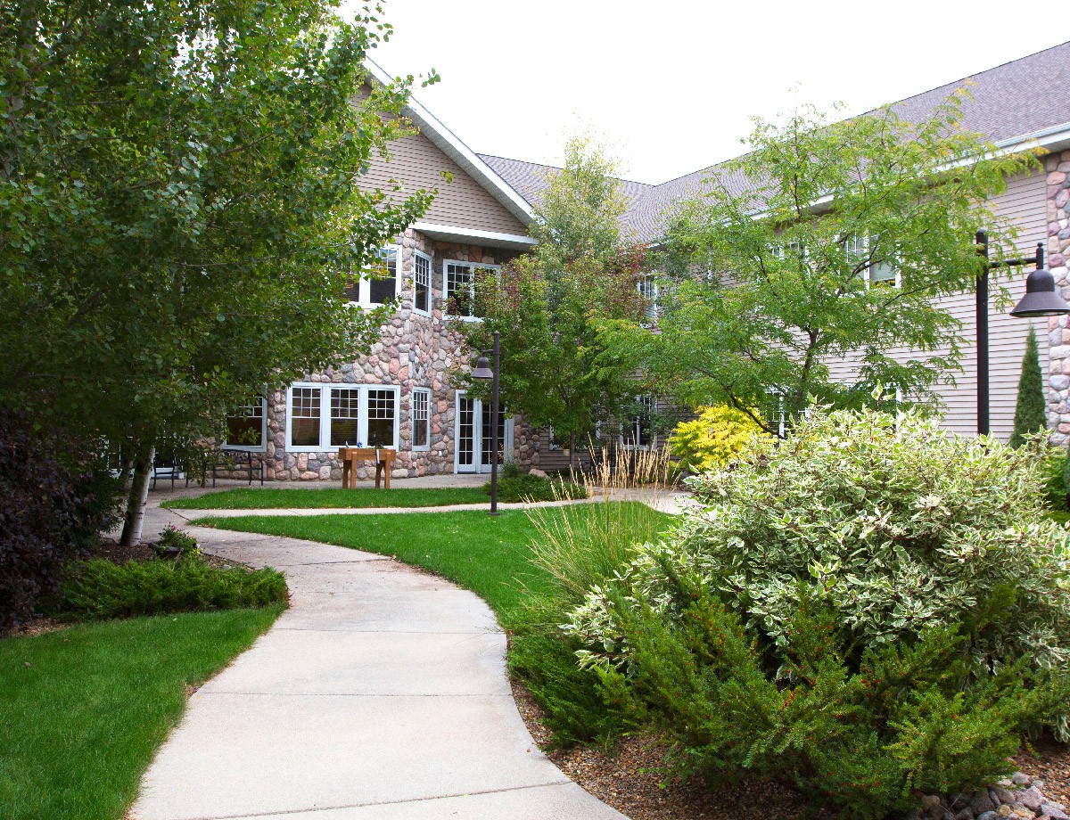 A scenic walkway leading to a residential building surrounded by lush greenery and trees.