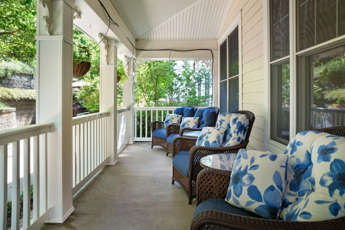 A cozy porch with wicker chairs and blue floral cushions, perfect for relaxing outdoors.
