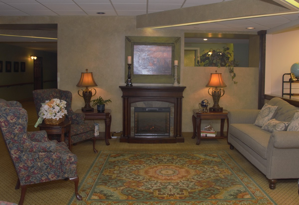 A cozy living room with a fireplace, armchairs, and decorative lamps.