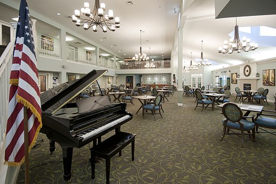 An elegant dining area with a grand piano and chandeliers.