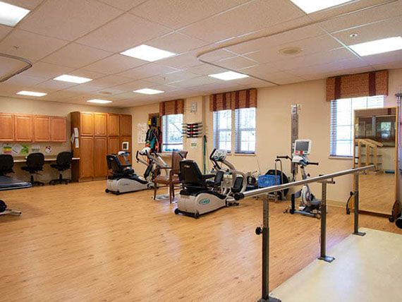 A rehabilitation therapy room equipped with exercise machines and parallel bars for physical therapy.
