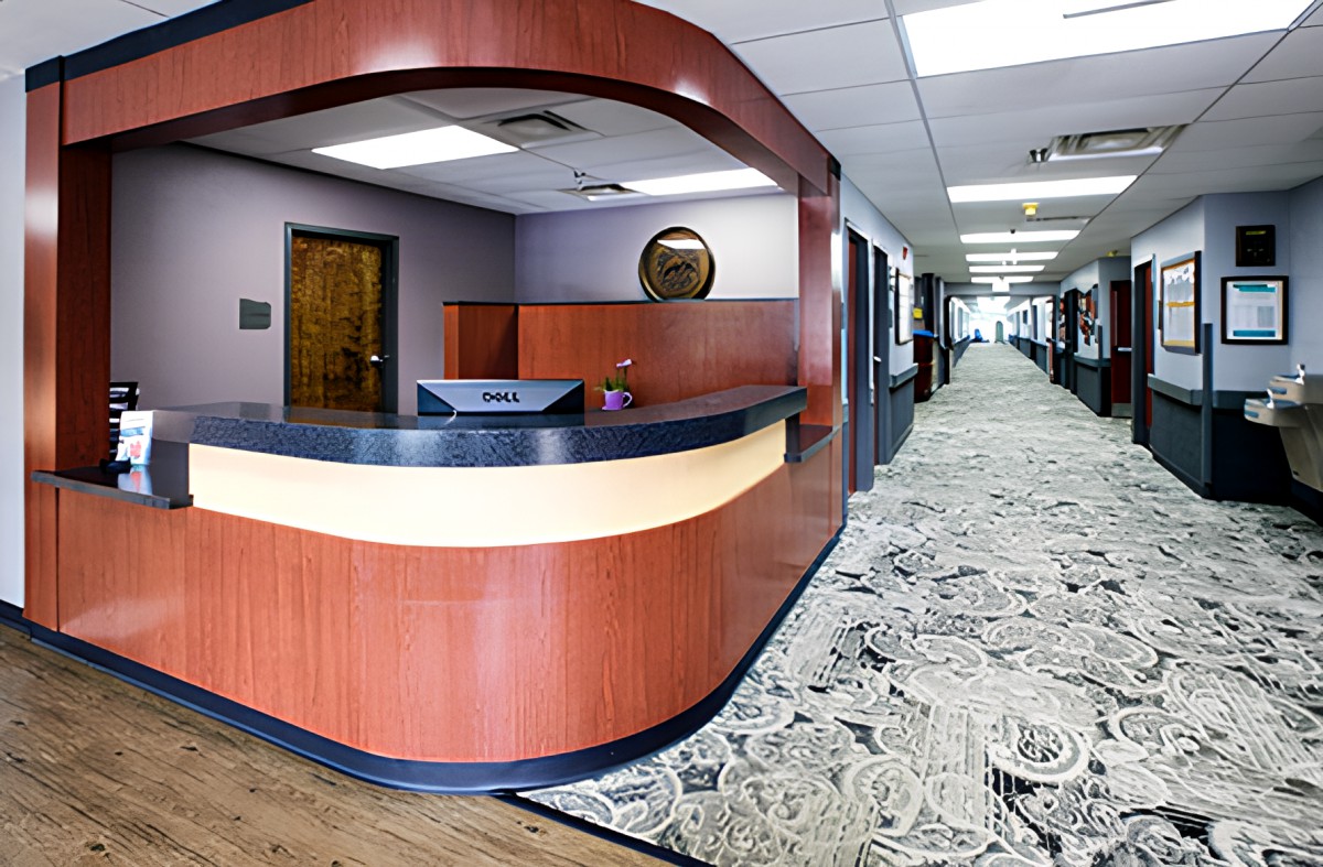 Modern office reception area with a desk and carpeted hallway.