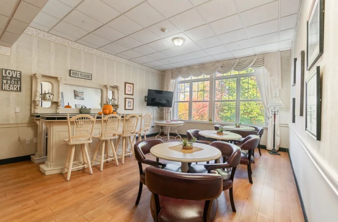 A cozy lounge area with seating, a TV, and large windows allowing natural light.