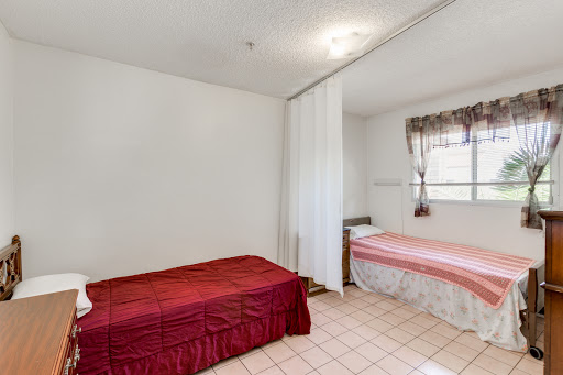 A simple bedroom featuring two beds with different bedding styles, separated by a curtain for privacy.