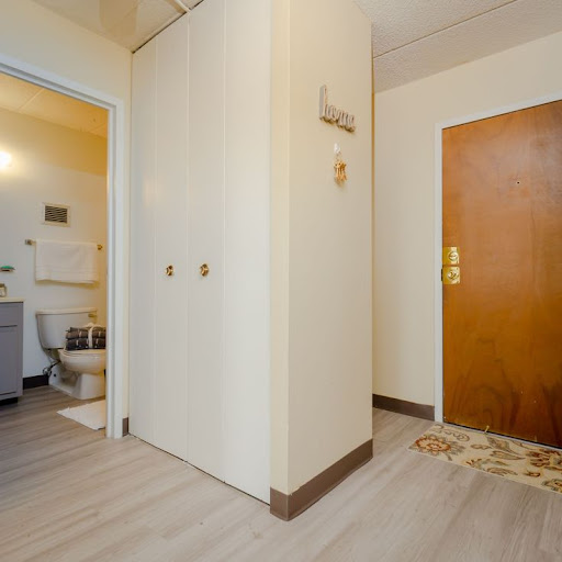 A view of an entrance hallway leading to a bathroom, featuring light-colored walls and wooden door.