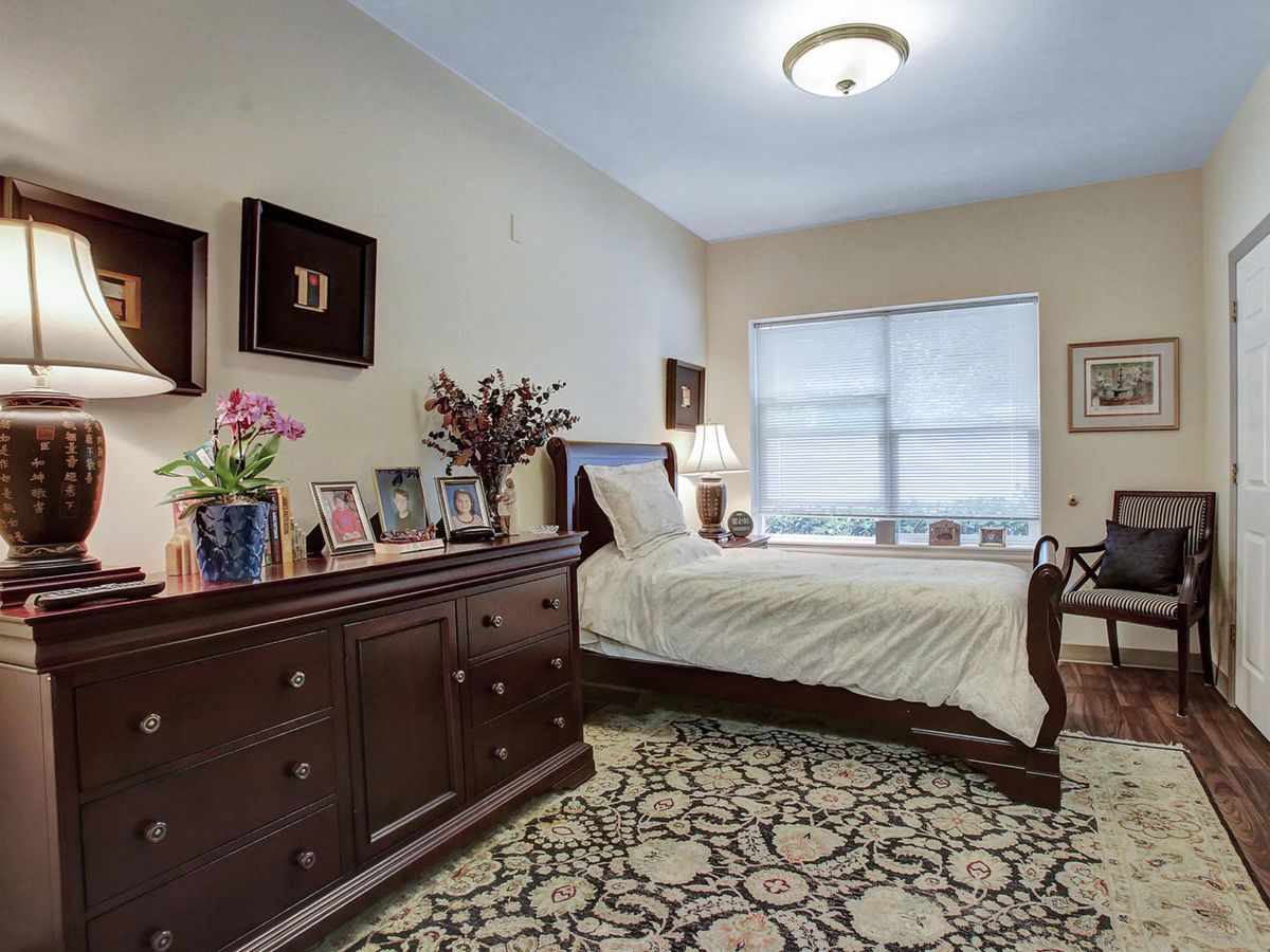 A cozy bedroom with a bed, wooden dresser, and decorative elements.
