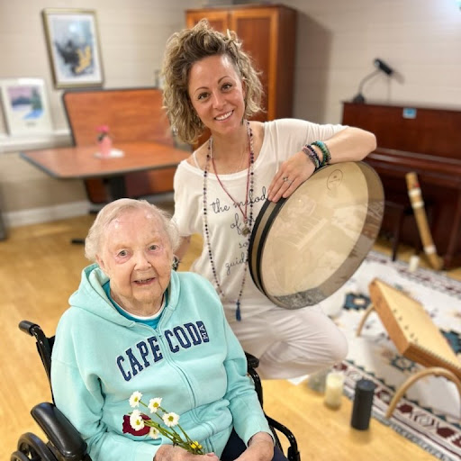 An uplifting moment of music therapy, where a caregiver engages joyfully with an elderly resident.