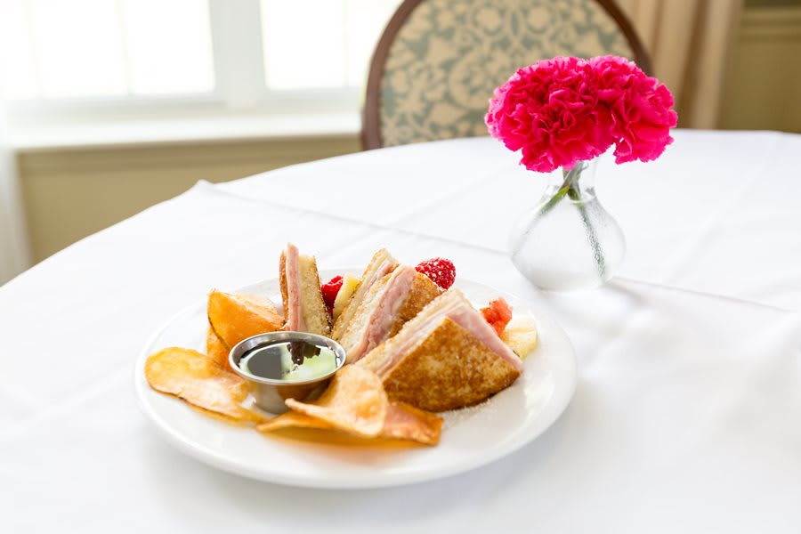 A plate of dessert pastries with dipping sauce, elegantly presented on a table with a floral centerpiece.