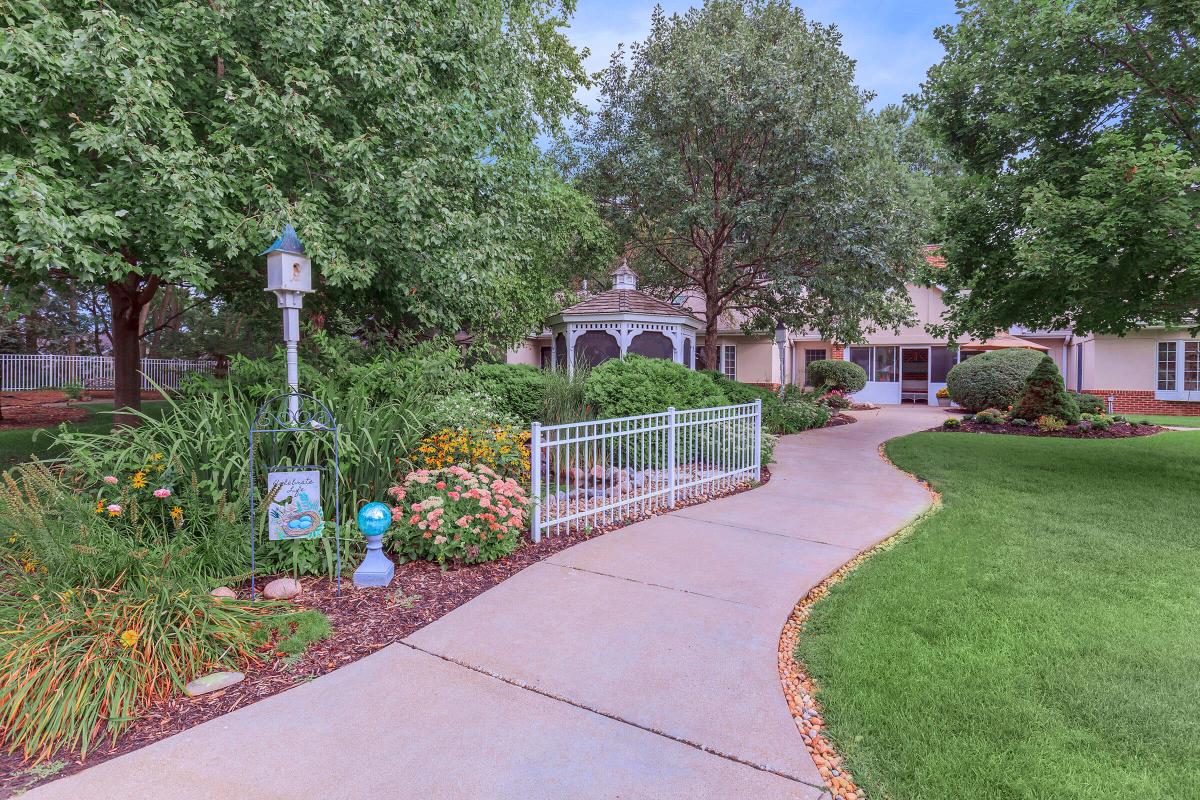 A scenic garden pathway surrounded by lush greenery and flowers.