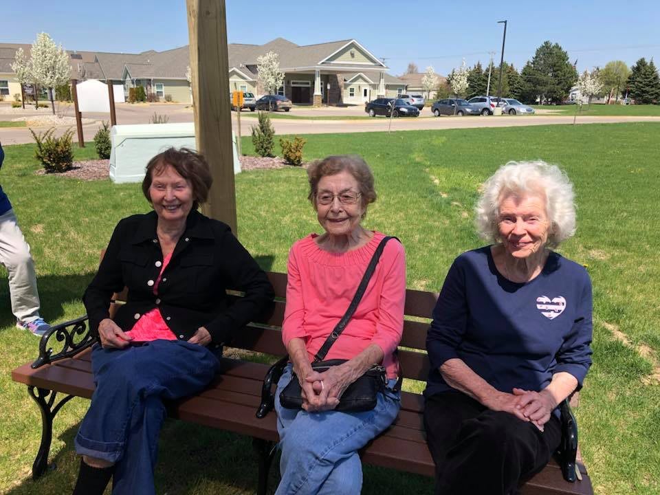 Three people sitting on a bench enjoying a sunny day in the park.