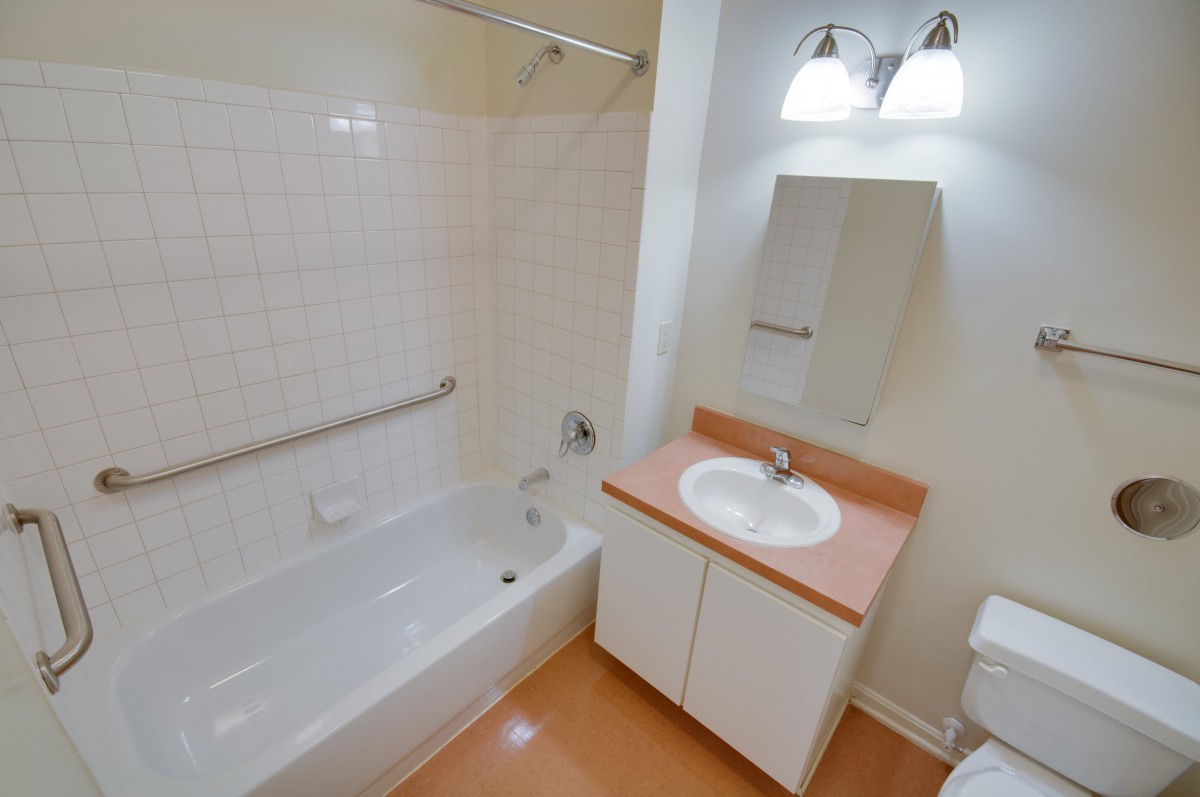 A clean and simple bathroom with a bathtub, sink, and vanity.