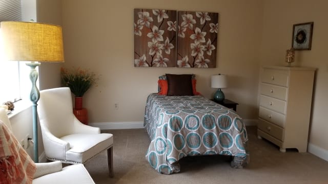 A cozy bedroom with a single bed, decorated with a patterned comforter and floral wall art.