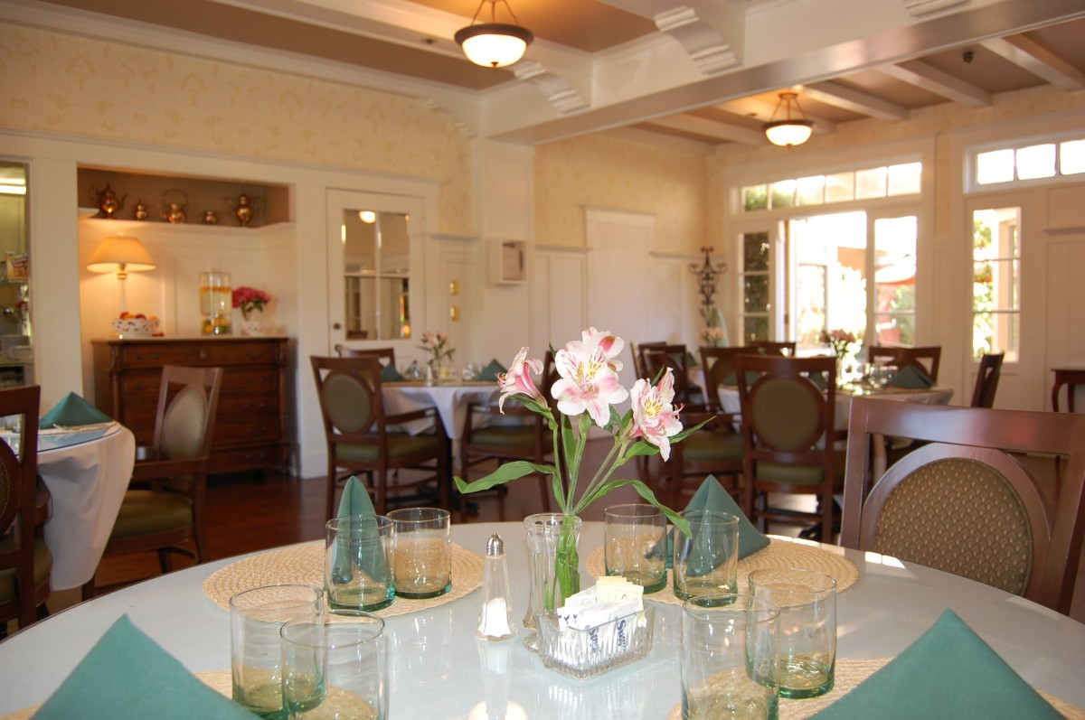 A well-lit dining room with an elegantly set table featuring flowers and glasses.