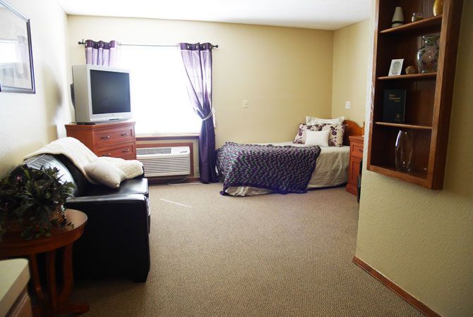 A cozy room featuring a bed, sofa, and television with ample natural light from the window.