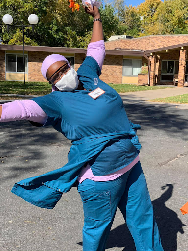 A joyful healthcare worker celebrating in scrubs outside.