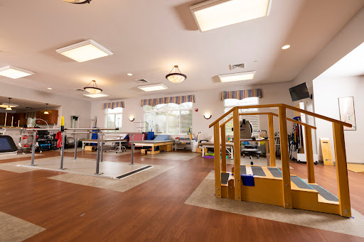 A bright and spacious physical therapy room equipped with various exercise devices for rehabilitation.