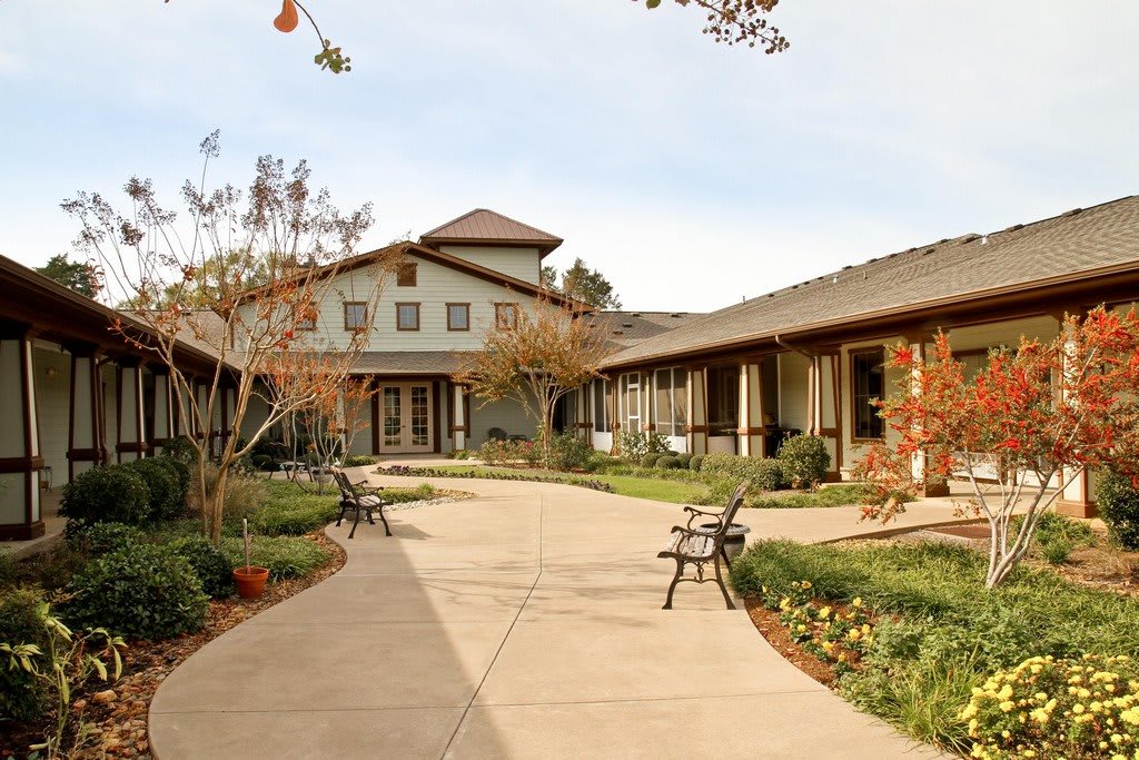 A serene courtyard surrounded by buildings, featuring benches and landscaped greenery.