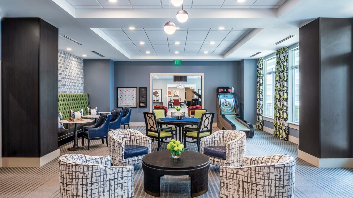 A modern recreational lounge featuring stylish seating, contemporary decor, and a game area.