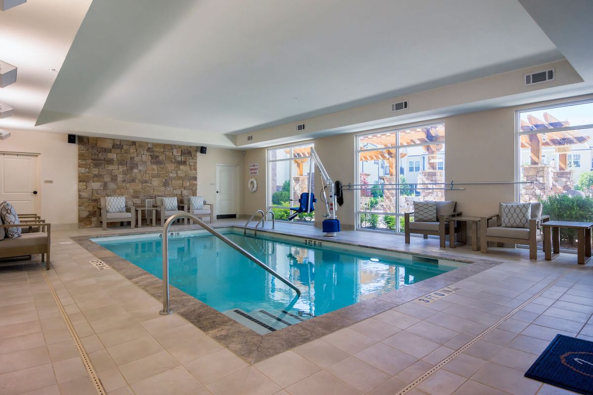 An indoor swimming pool with seating and large windows providing natural light.