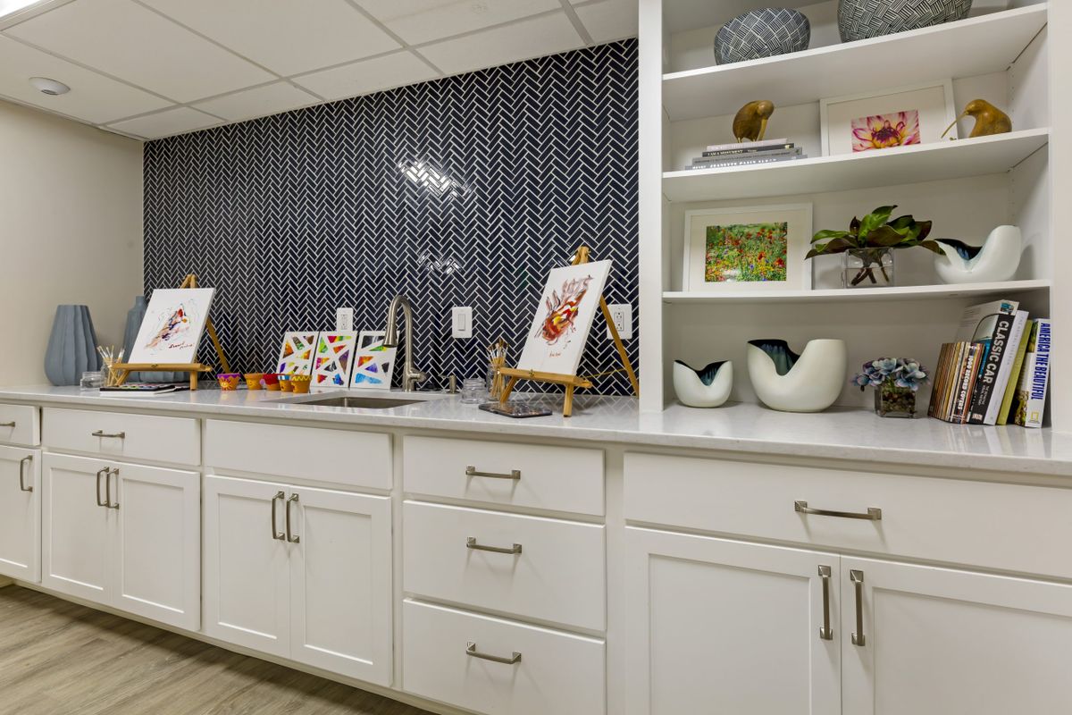 A well-organized kitchen space featuring white cabinets, decorative shelves, and a tiled backsplash.