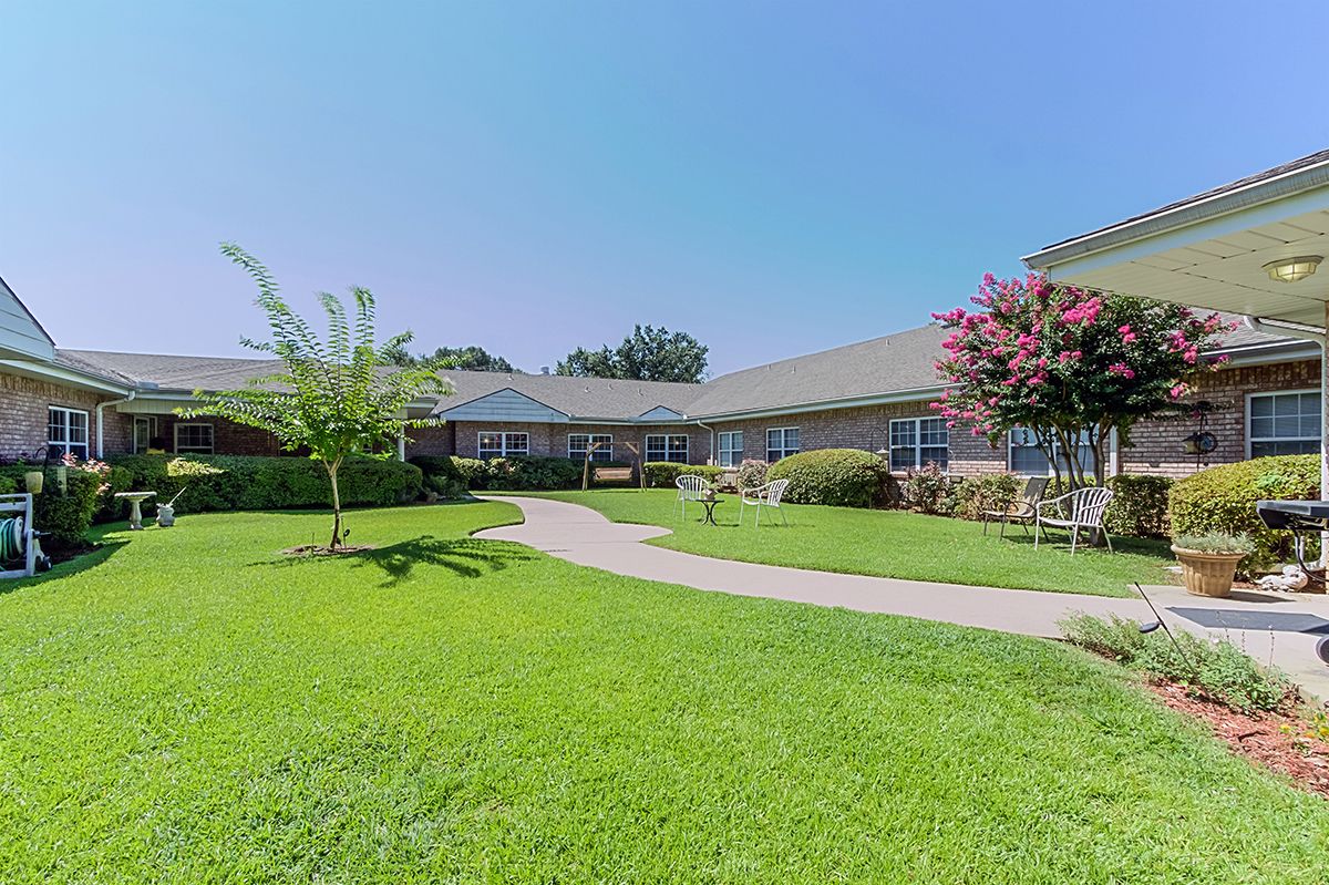A serene view of a building surrounded by lush greenery and a clear blue sky.