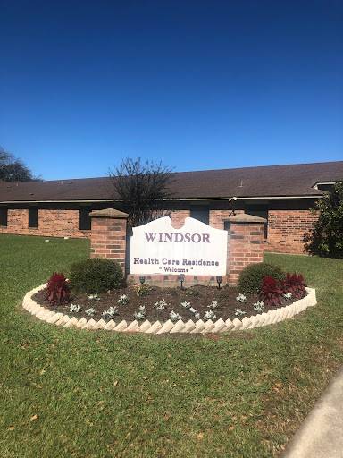 A well-maintained entrance sign for Windsor, featuring a flowerbed and clear blue skies.