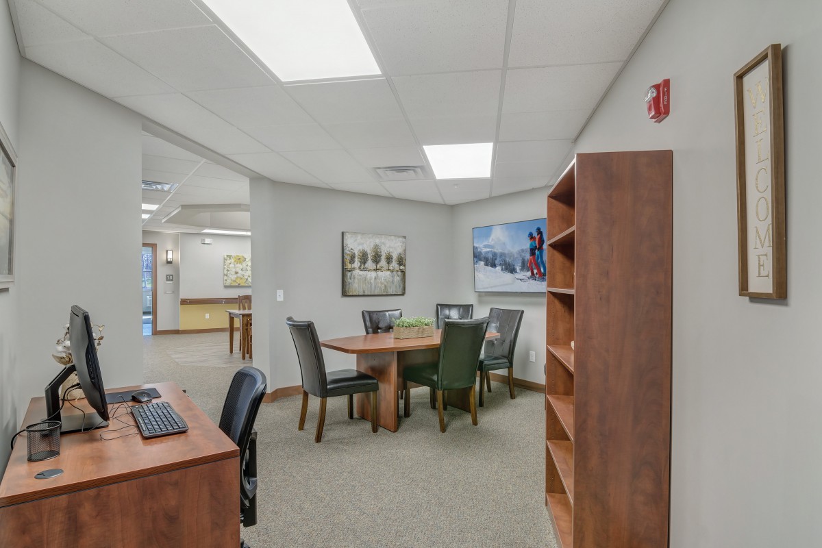 A spacious office meeting room with a wooden table, chairs, and shelves.