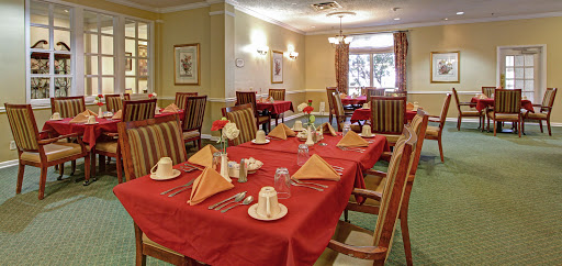 A beautifully arranged dining room featuring red table settings and fresh flowers.