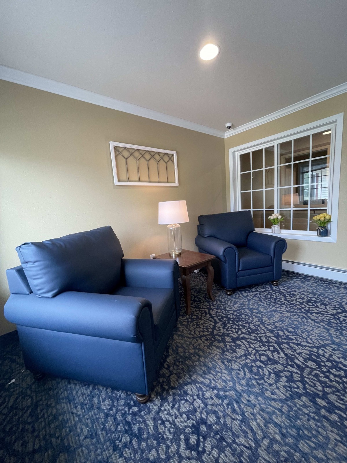 A cozy living room with blue armchairs and a lamp by the window.