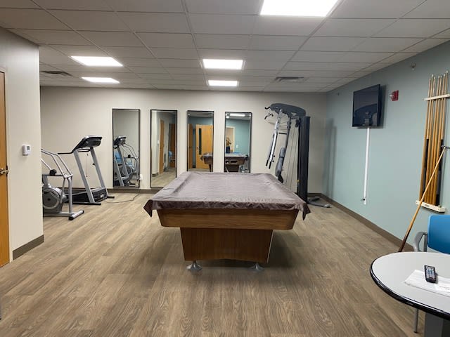 A multi-purpose indoor room featuring gym equipment and a pool table.
