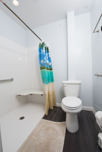 A modern bathroom featuring a shower, toilet, and a vibrant beach-themed shower curtain.