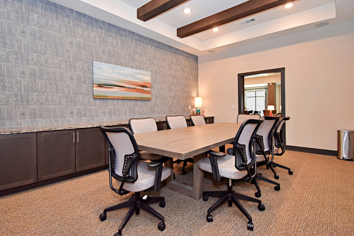 A modern conference room with a large meeting table and office chairs.