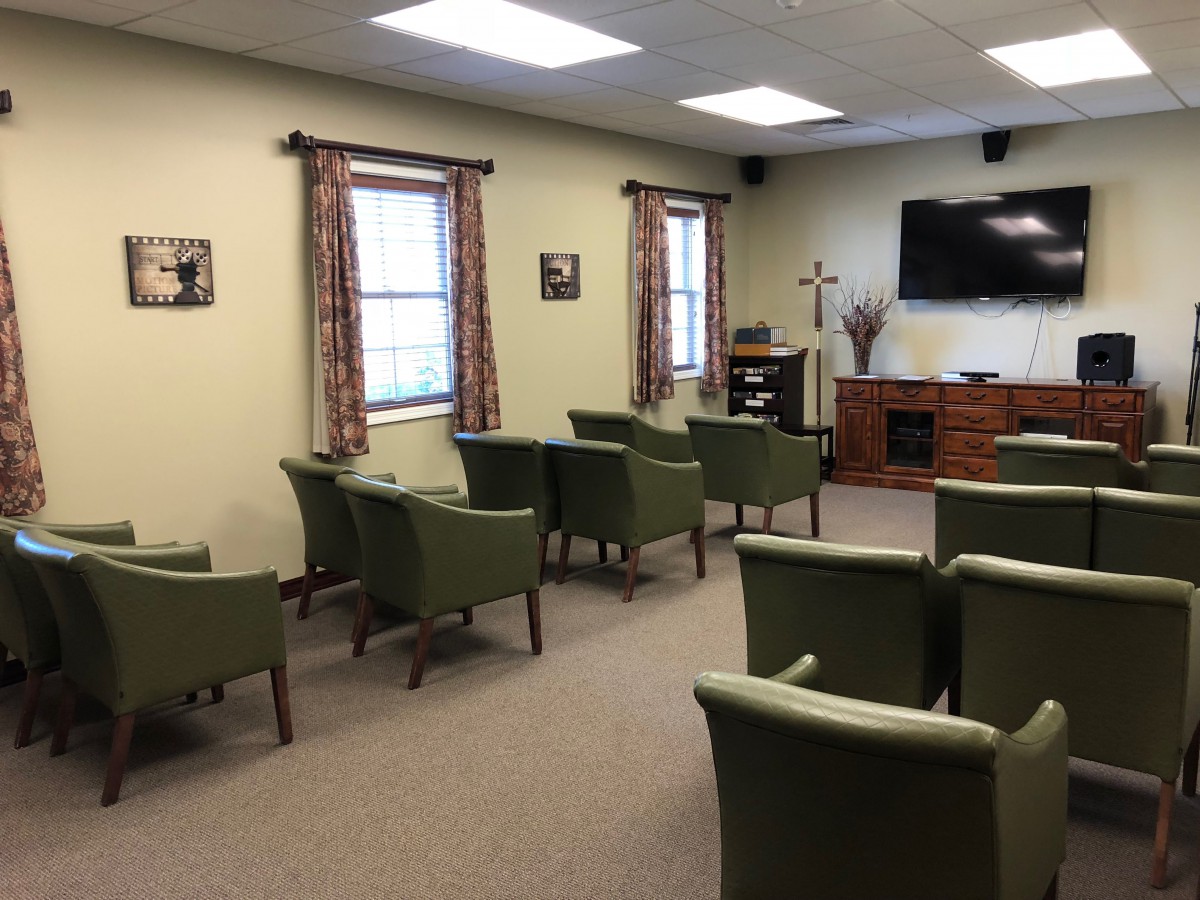 A cozy meeting room with green chairs and a television.